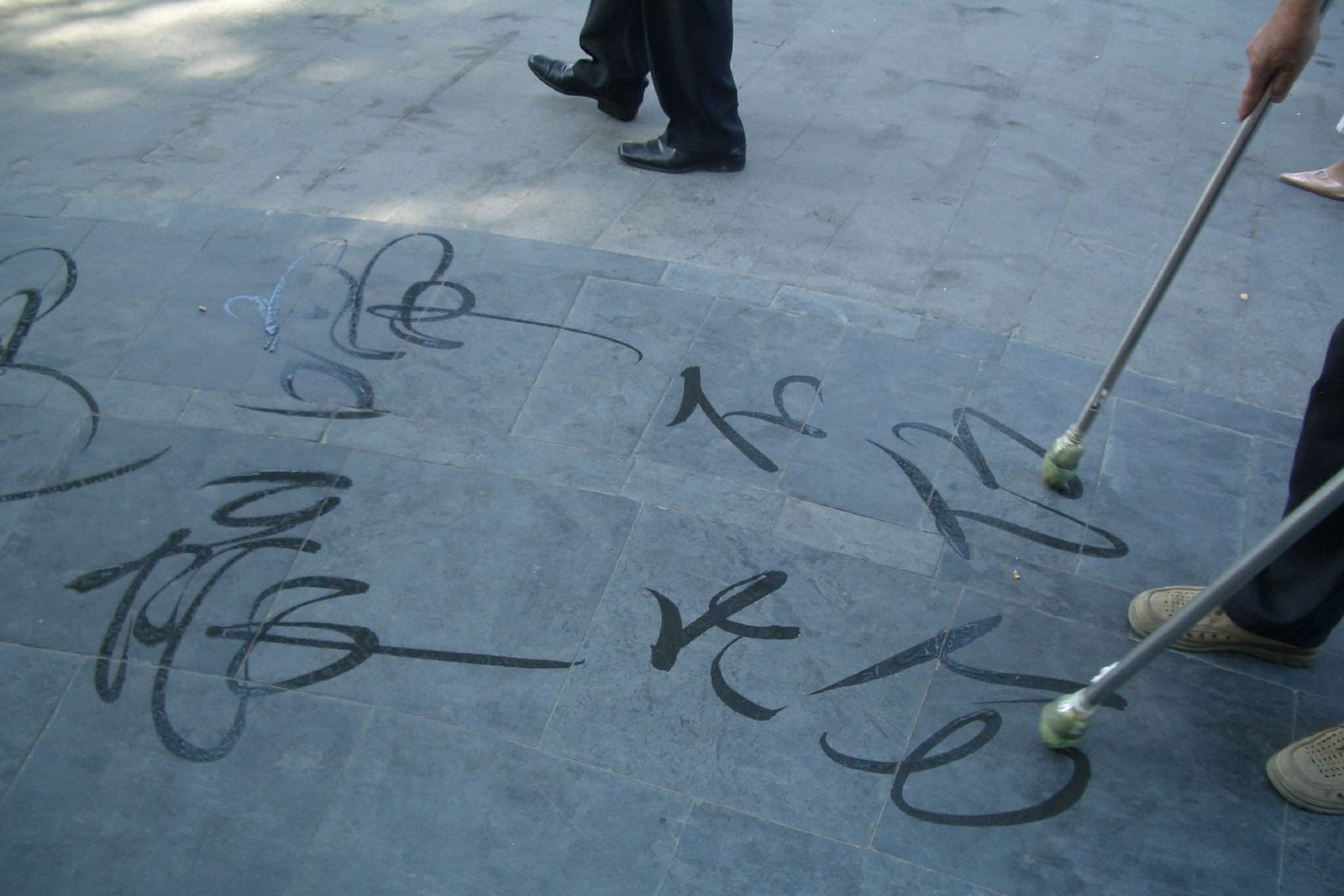 Chinese calligraphy characters brushed in water onto a stone pavement