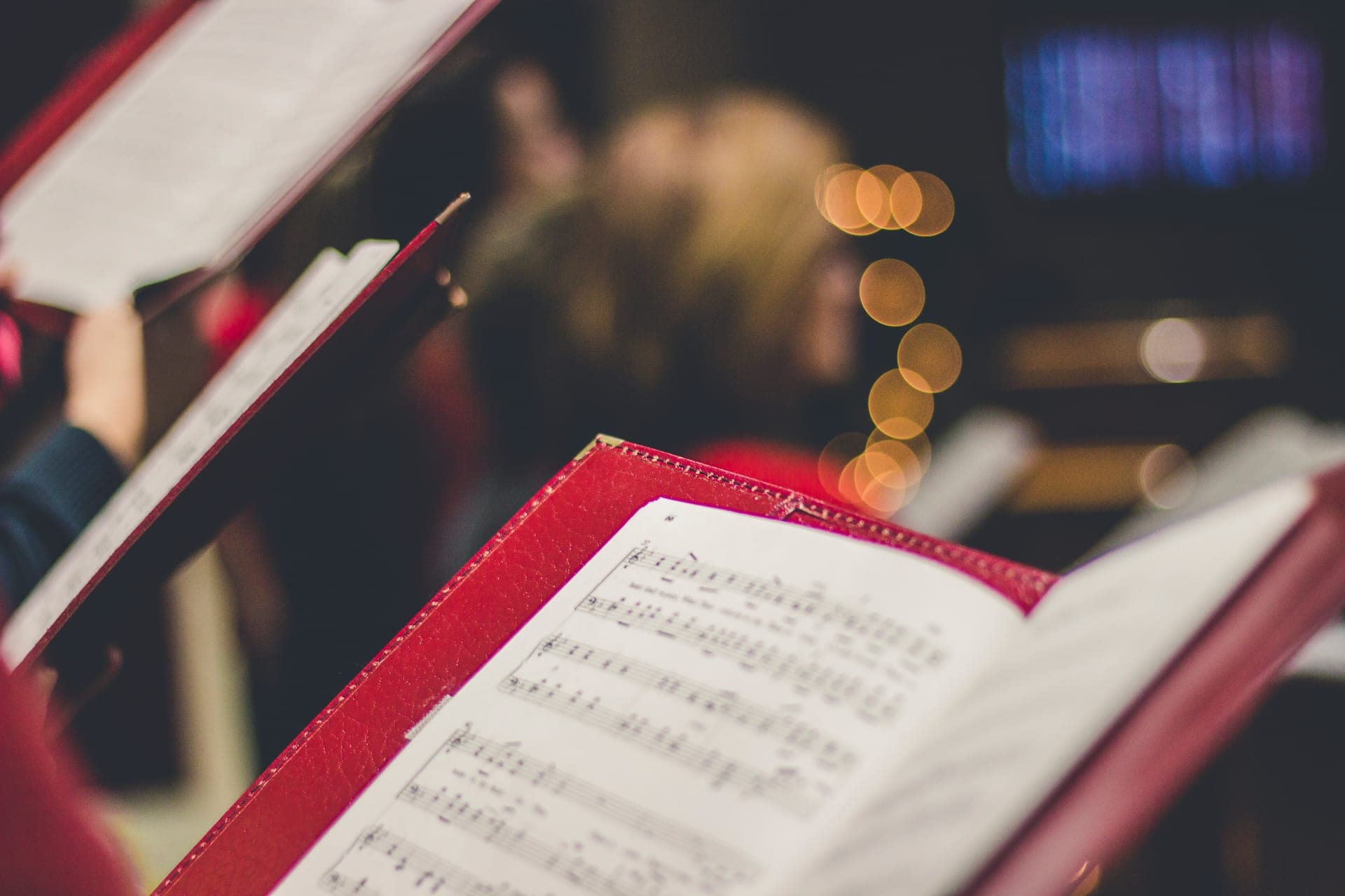 Open sheet music on a music stand with warm bokeh lights behind